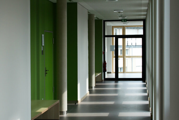 Schulflur mit weißen Wänden und grünen Türen